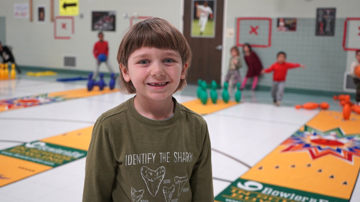 student standing in gymnasium with bowling in background
