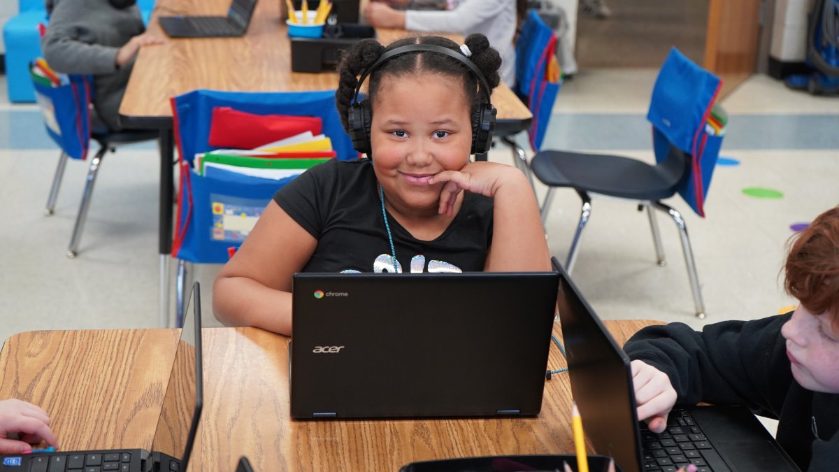 girl smiling behind laptop screen