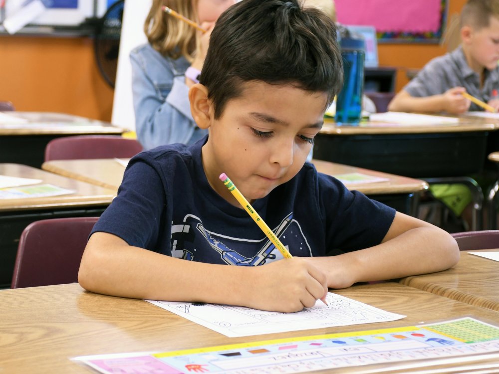 A student writes at his desk