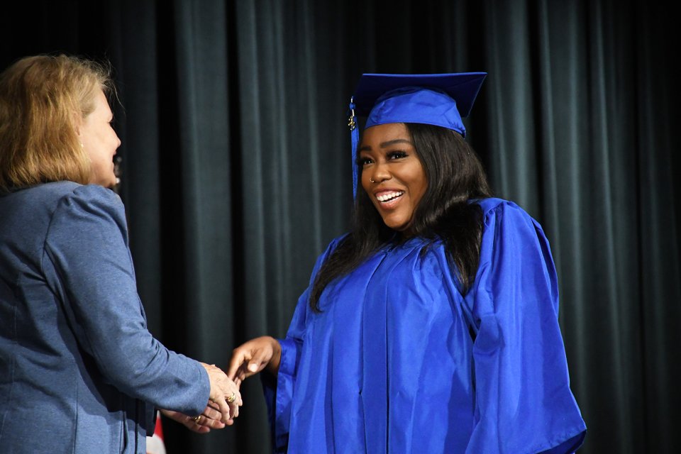 student in cap and gown smiling