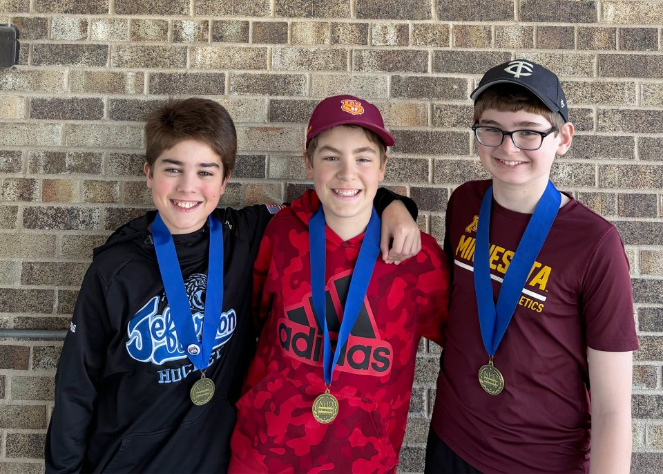 Three students wearing their first place medals