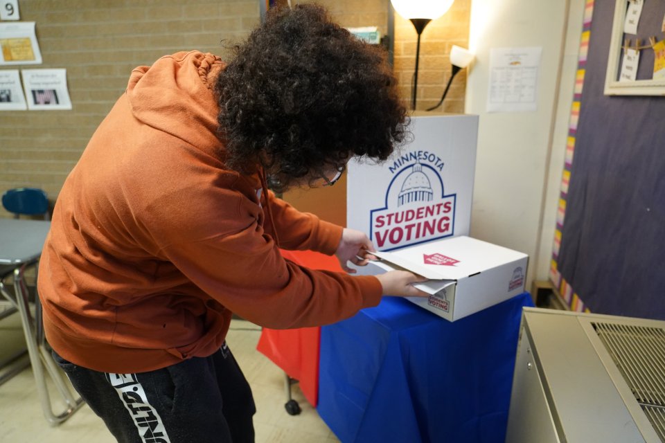student placing mock election ballot in ballot box