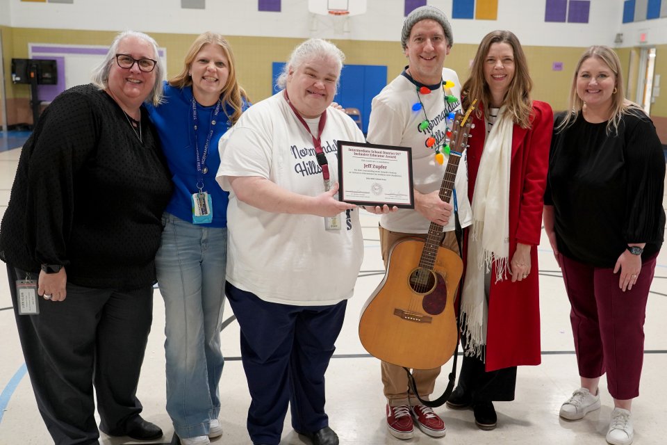 Inclusive Educator award recipient holding award and guitar. Standing with other educators