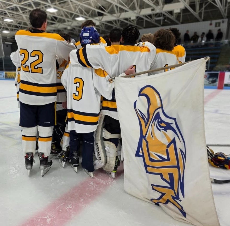Kennedy hockey players huddle with team flag