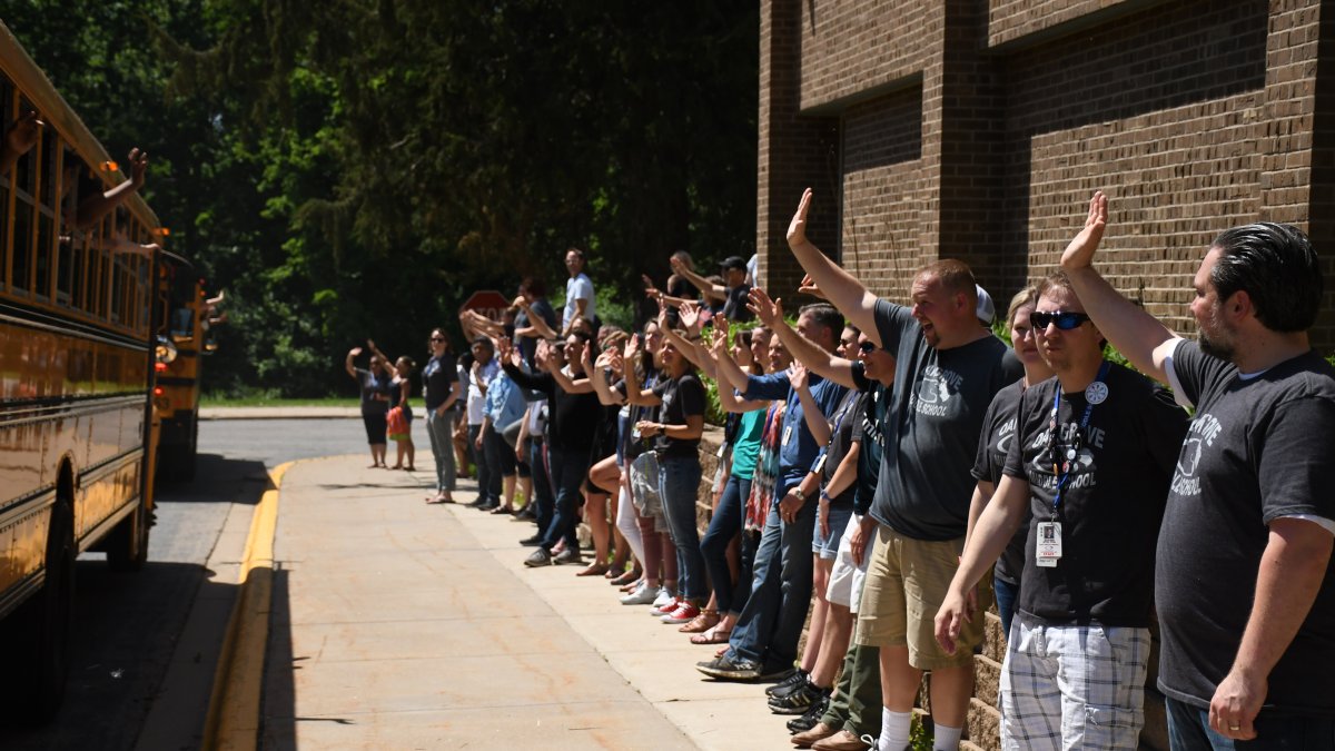 Staff members wave to departing buses