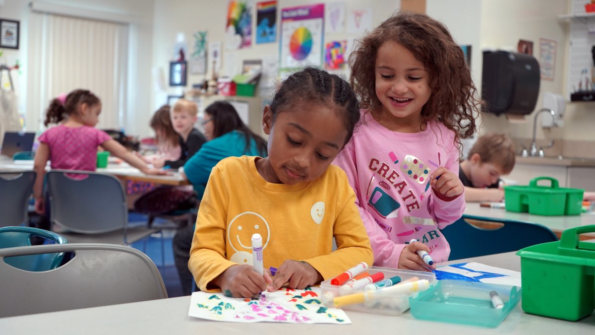 two students drawing with markers
