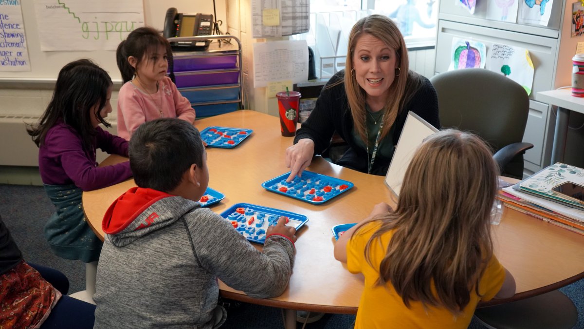 teacher with four students sitting around her at a table