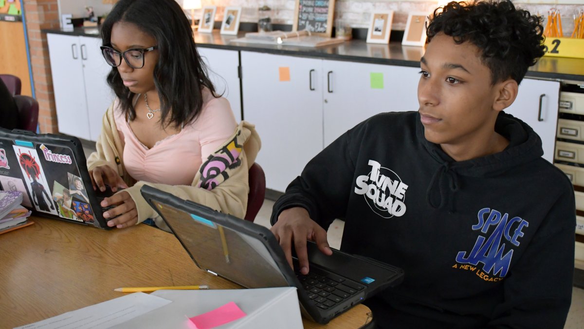 two students working on laptops in class