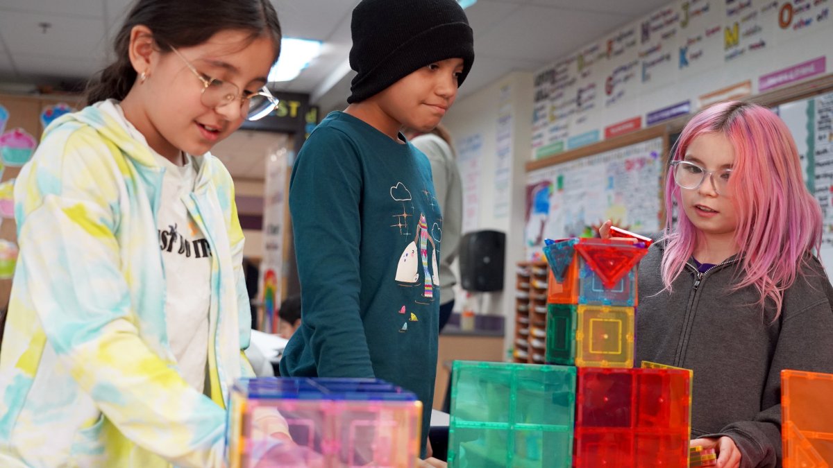 three students building colorful castle