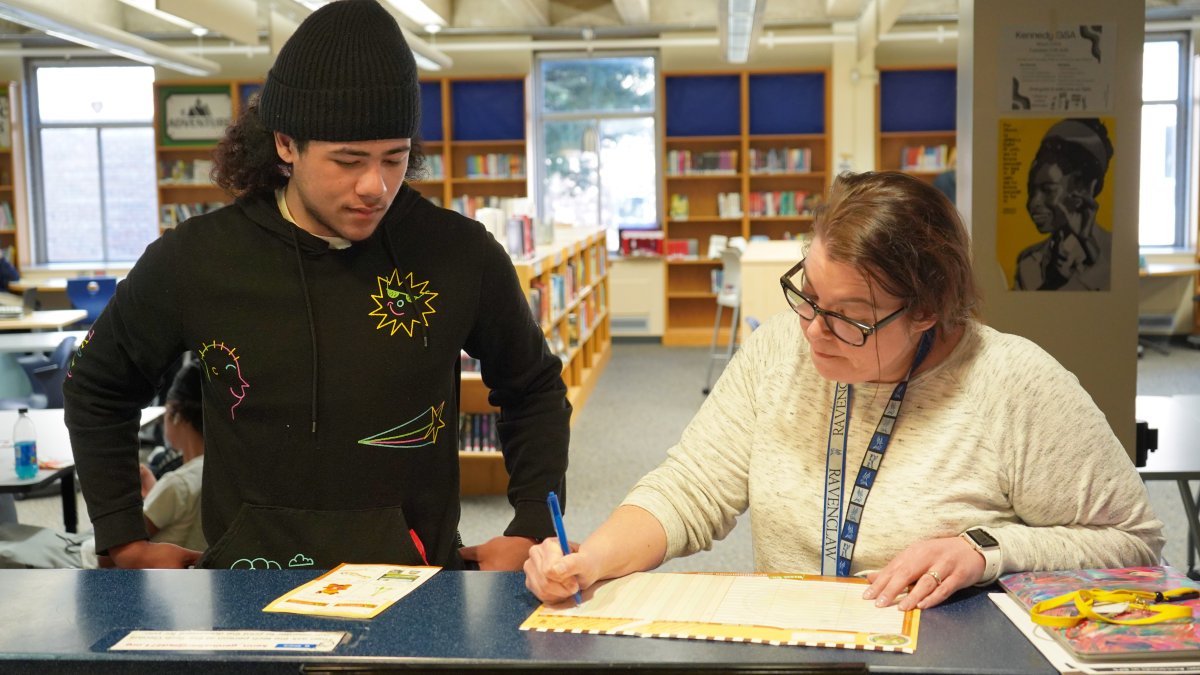 student talking with teacher in media center