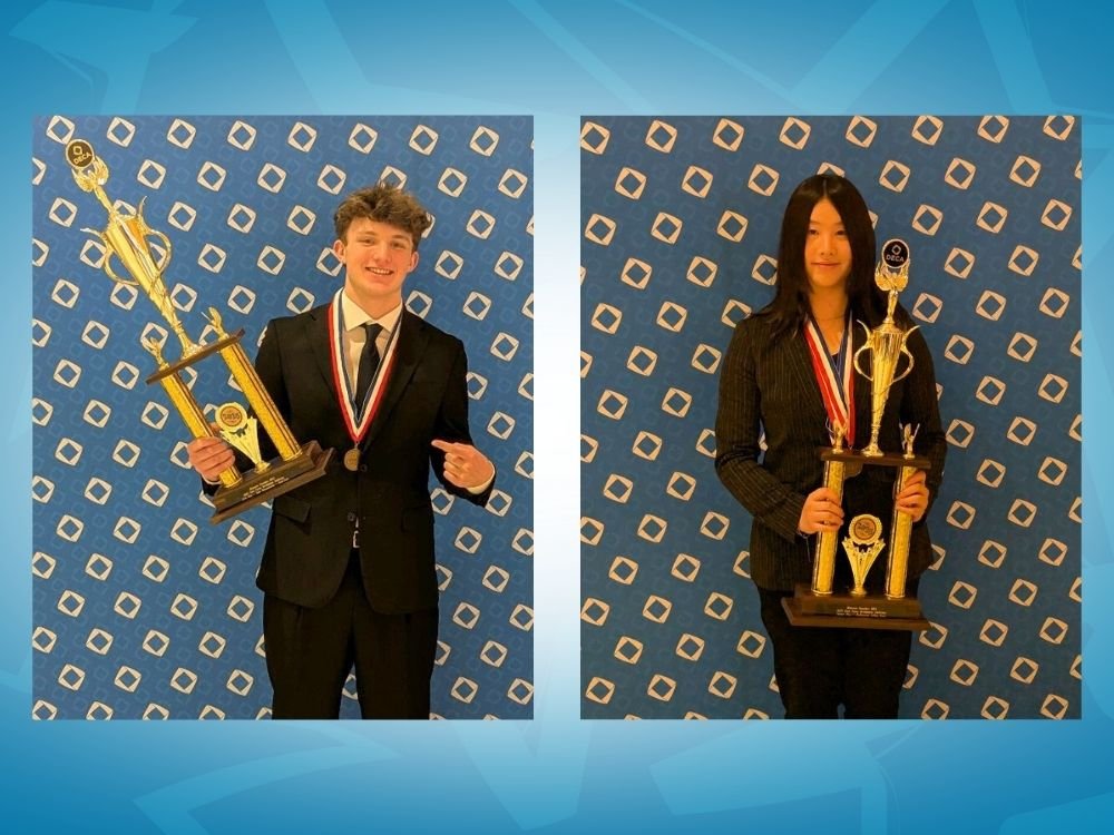 Two students wearing suit coats and medals while holding trophies