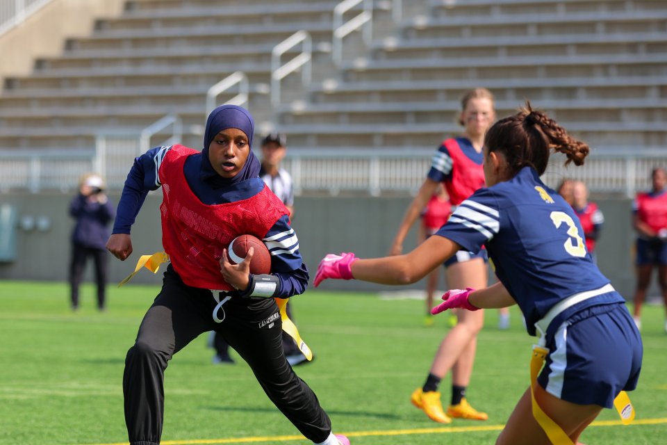 girl playing flag football running with the ball