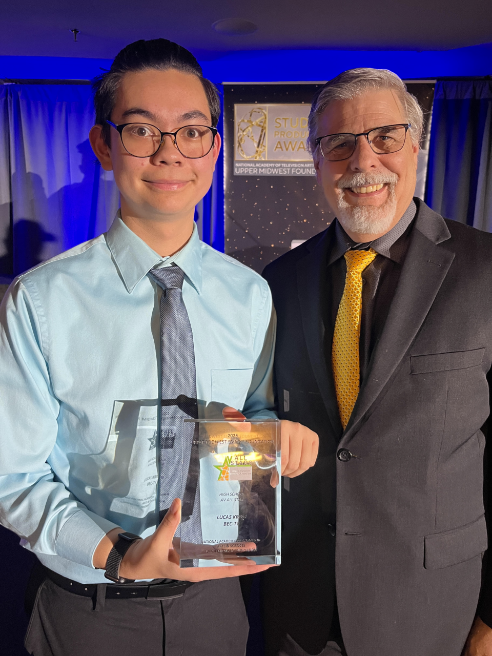 student and staff member holding clear transparent award trophy